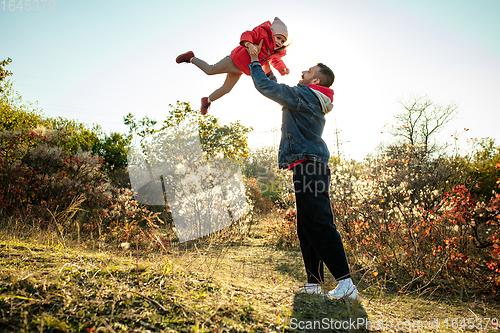 Image of Happy father and little cute daughter walking down the forest path in autumn sunny day