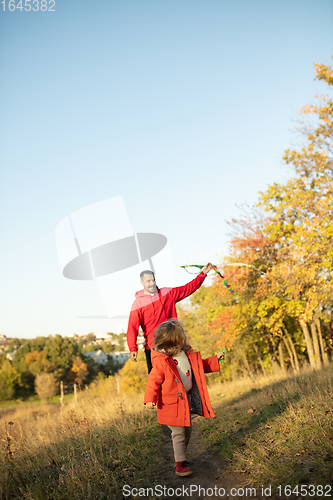 Image of Happy father and little cute daughter walking down the forest path in autumn sunny day