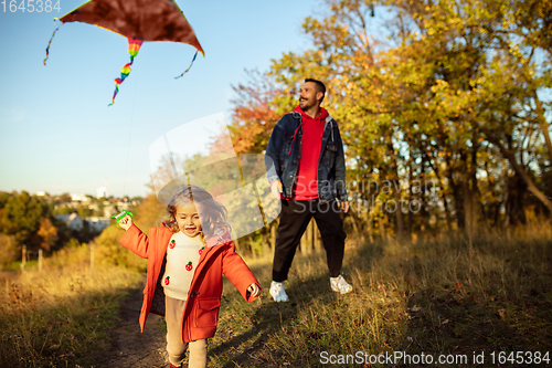 Image of Happy father and little cute daughter walking down the forest path in autumn sunny day