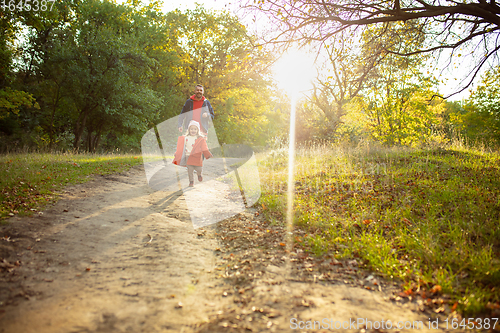 Image of Happy father and little cute daughter walking down the forest path in autumn sunny day