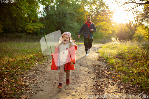 Image of Happy father and little cute daughter walking down the forest path in autumn sunny day