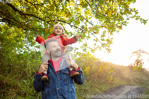 Image of Happy father and little cute daughter walking down the forest path in autumn sunny day