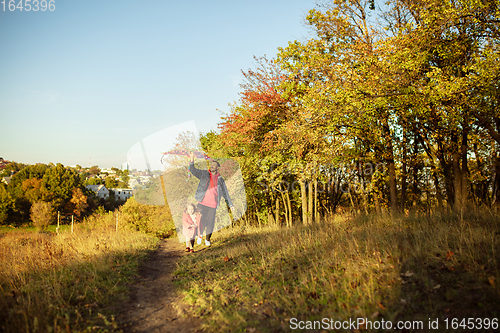 Image of Happy father and little cute daughter walking down the forest path in autumn sunny day