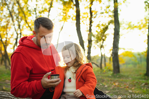 Image of Happy father and little cute daughter walking down the forest path in autumn sunny day