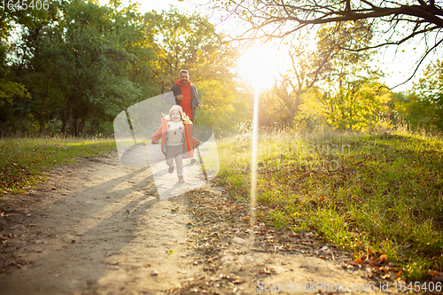 Image of Happy father and little cute daughter walking down the forest path in autumn sunny day