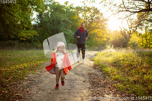 Image of Happy father and little cute daughter walking down the forest path in autumn sunny day