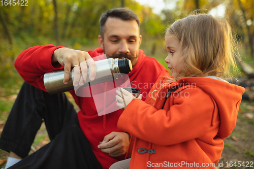 Image of Happy father and little cute daughter walking down the forest path in autumn sunny day