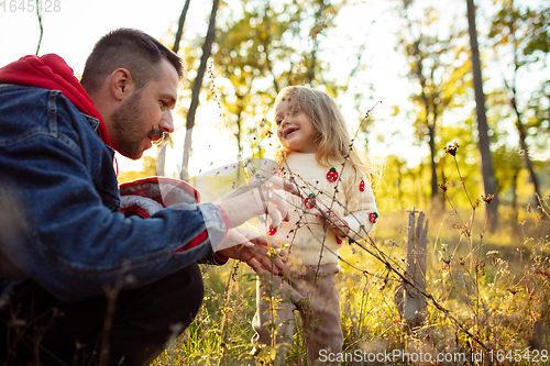 Image of Happy father and little cute daughter walking down the forest path in autumn sunny day