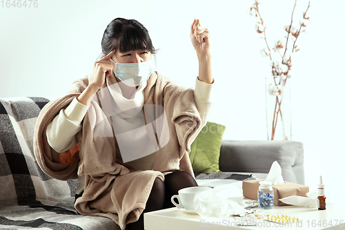 Image of Woman wrapped in a plaid and wearing face mask trying to protect herself from somebody\'s sick near by