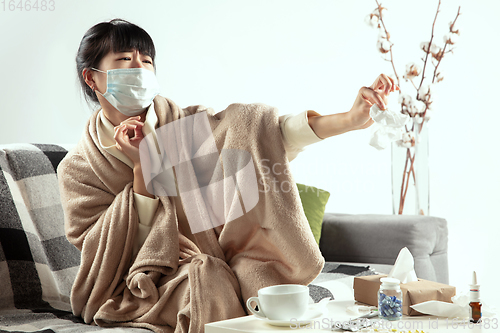 Image of Woman wrapped in a plaid and wearing face mask trying to protect herself from somebody\'s sick near by