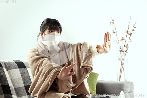 Image of Woman wrapped in a plaid and wearing face mask trying to protect herself from somebody\'s sick near by