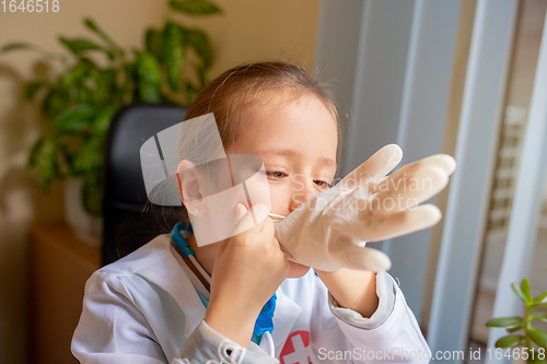 Image of Paediatrician doctor examining a child in comfortabe medical office. Little girl playing pretends like doctor for woman