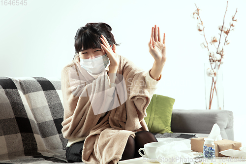 Image of Woman wrapped in a plaid and wearing face mask trying to protect herself from somebody\'s sick near by