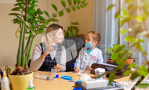 Image of Paediatrician doctor examining a child in comfortabe medical office. Little girl playing pretends like doctor for woman