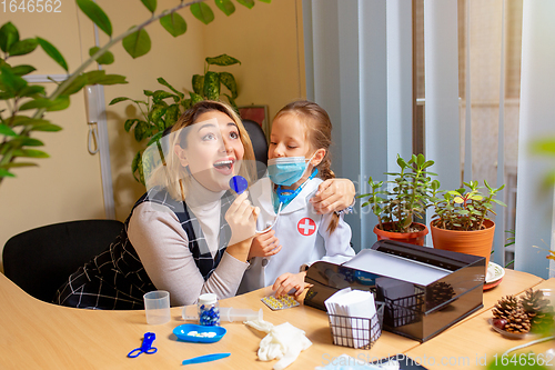 Image of Paediatrician doctor examining a child in comfortabe medical office. Little girl playing pretends like doctor for woman