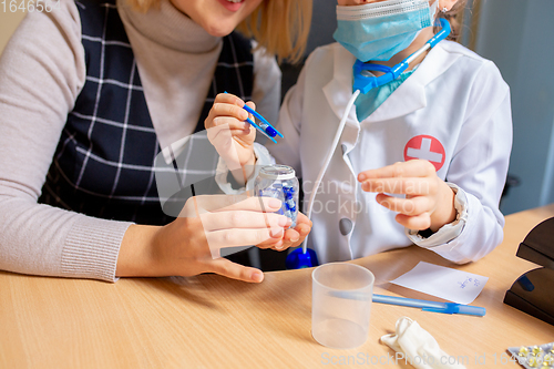 Image of Paediatrician doctor examining a child in comfortabe medical office. Little girl playing pretends like doctor for woman