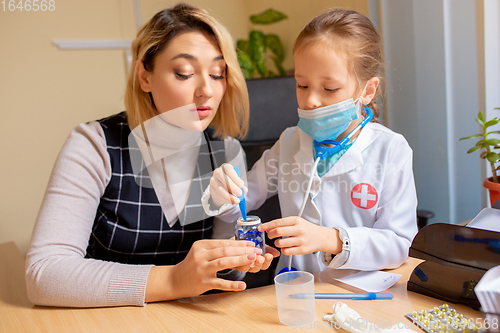 Image of Paediatrician doctor examining a child in comfortabe medical office. Little girl playing pretends like doctor for woman