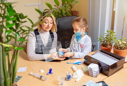 Image of Paediatrician doctor examining a child in comfortabe medical office. Little girl playing pretends like doctor for woman