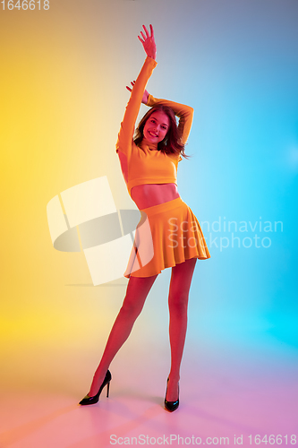 Image of Beautiful seductive girl in fashionable, romantic yellow outfit on bright gradient yellow-blue background in neon light