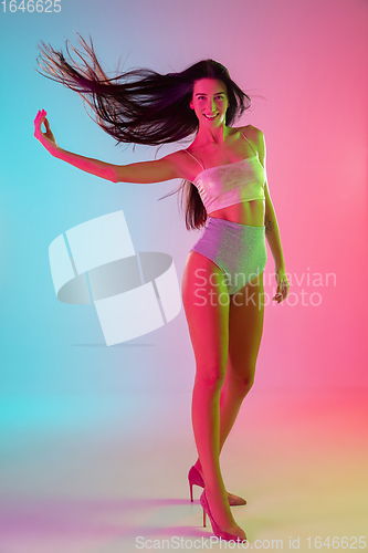 Image of Beautiful seductive girl in fashionable swimsuit on bright gradient pink-blue background in neon light