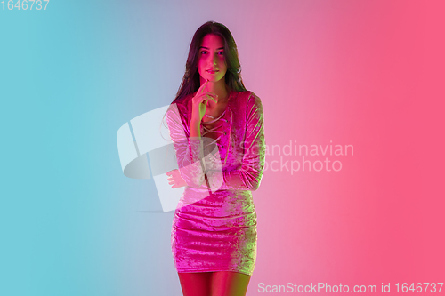 Image of Beautiful seductive girl in fashionable dress, outfit on bright gradient pink-blue background in neon light