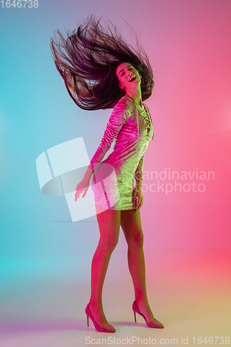 Image of Beautiful seductive girl in fashionable dress, outfit on bright gradient pink-blue background in neon light