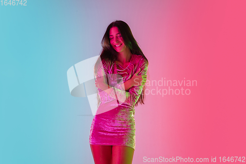 Image of Beautiful seductive girl in fashionable dress, outfit on bright gradient pink-blue background in neon light