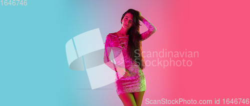 Image of Beautiful seductive girl in fashionable dress, outfit on bright gradient pink-blue background in neon light