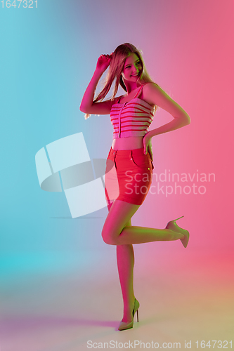 Image of Beautiful girl in fashionable, romantic outfit on bright gradient pink-blue background in neon light