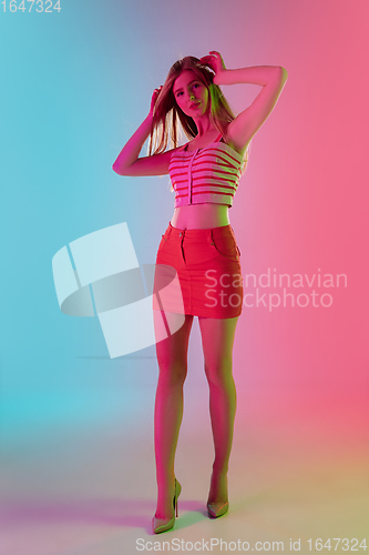 Image of Beautiful girl in fashionable, romantic outfit on bright gradient pink-blue background in neon light