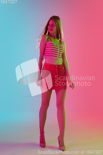 Image of Beautiful girl in fashionable, romantic outfit on bright gradient pink-blue background in neon light