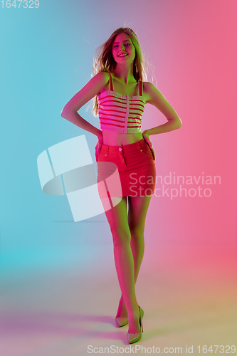 Image of Beautiful girl in fashionable, romantic outfit on bright gradient pink-blue background in neon light