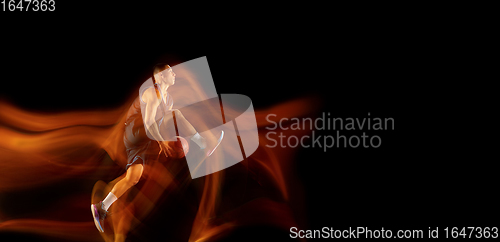 Image of Young east asian basketball player in action and jump in mixed light over dark studio background. Concept of sport, movement, energy and dynamic, healthy lifestyle.