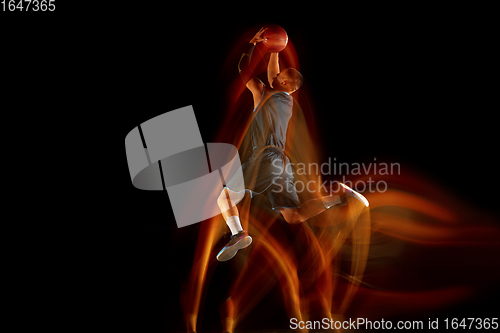 Image of Young east asian basketball player in action and jump in mixed light over dark studio background. Concept of sport, movement, energy and dynamic, healthy lifestyle.