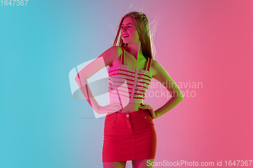 Image of Beautiful girl in fashionable, romantic outfit on bright gradient pink-blue background in neon light