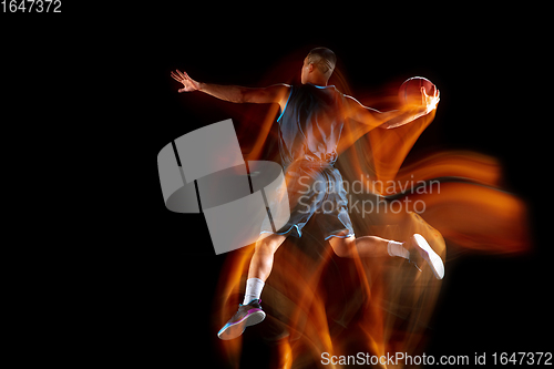 Image of Young east asian basketball player in action and jump in mixed light over dark studio background. Concept of sport, movement, energy and dynamic, healthy lifestyle.