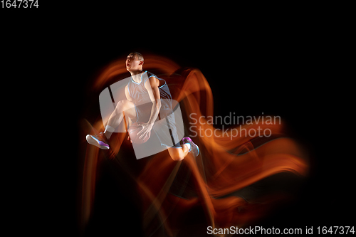 Image of Young east asian basketball player in action and jump in mixed light over dark studio background. Concept of sport, movement, energy and dynamic, healthy lifestyle.