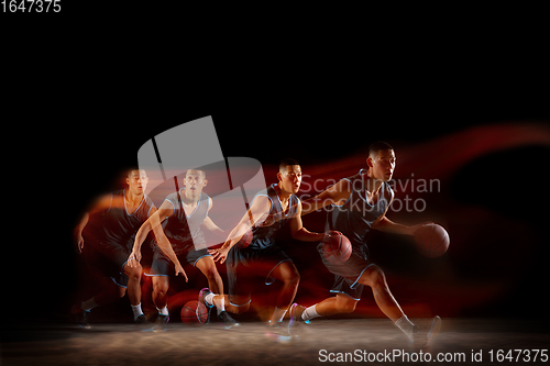 Image of Young east asian basketball player in action and jump in mixed strobe light over dark studio background. Concept of sport, movement, energy and dynamic, healthy lifestyle.