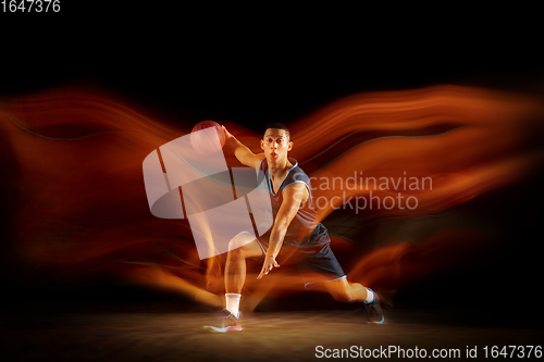 Image of Young east asian basketball player in action and jump in mixed light over dark studio background. Concept of sport, movement, energy and dynamic, healthy lifestyle.