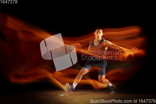 Image of Young east asian basketball player in action and jump in mixed light over dark studio background. Concept of sport, movement, energy and dynamic, healthy lifestyle.