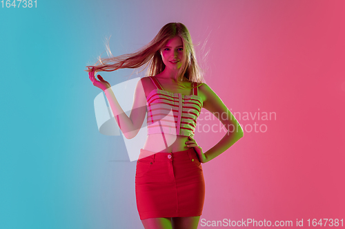 Image of Beautiful girl in fashionable, romantic outfit on bright gradient pink-blue background in neon light