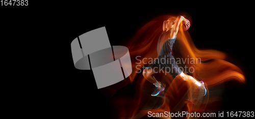 Image of Young east asian basketball player in action and jump in mixed light over dark studio background. Concept of sport, movement, energy and dynamic, healthy lifestyle.