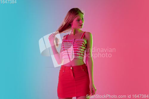 Image of Beautiful girl in fashionable, romantic outfit on bright gradient pink-blue background in neon light