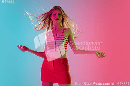 Image of Beautiful girl in fashionable, romantic outfit on bright gradient pink-blue background in neon light