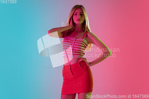 Image of Beautiful girl in fashionable, romantic outfit on bright gradient pink-blue background in neon light