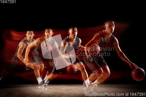 Image of Young east asian basketball player in action and jump in mixed strobe light over dark studio background. Concept of sport, movement, energy and dynamic, healthy lifestyle.