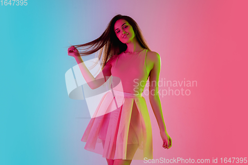 Image of Beautiful seductive girl in fashionable, romantic outfit on bright gradient pink-blue background in neon light