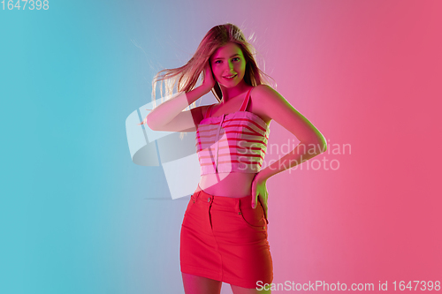 Image of Beautiful girl in fashionable, romantic outfit on bright gradient pink-blue background in neon light