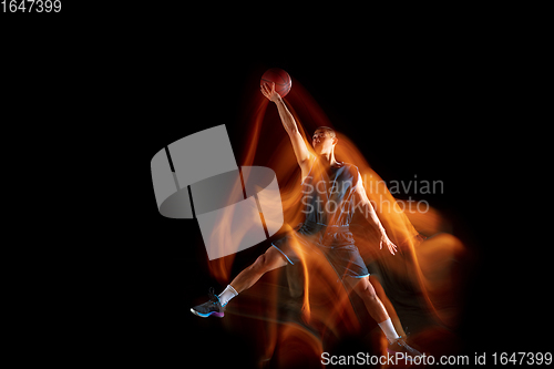 Image of Young east asian basketball player in action and jump in mixed light over dark studio background. Concept of sport, movement, energy and dynamic, healthy lifestyle.