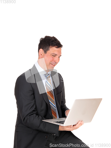 Image of Happy businessman sitting with his laptop